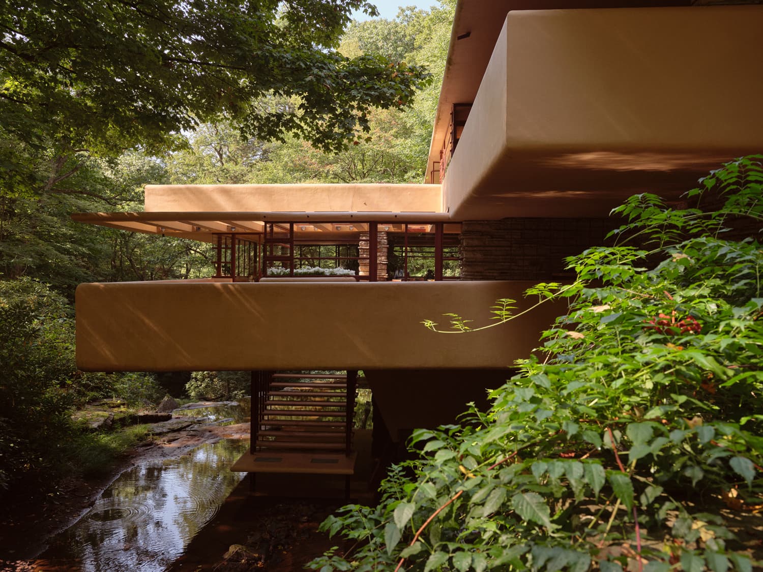 Cantilevered balconies of Fallingwater seen from below with staircase descending toward the stream