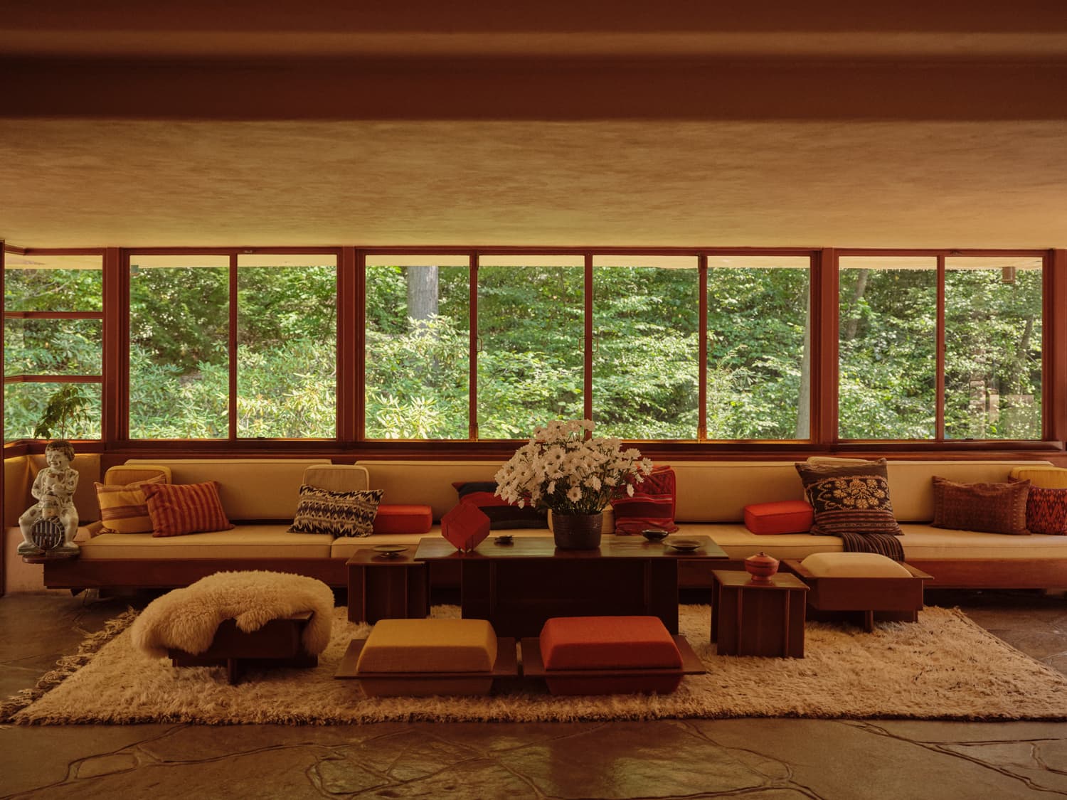 Fallingwater living room with built in seating, colorful cushions, and ribbon windows overlooking the woods