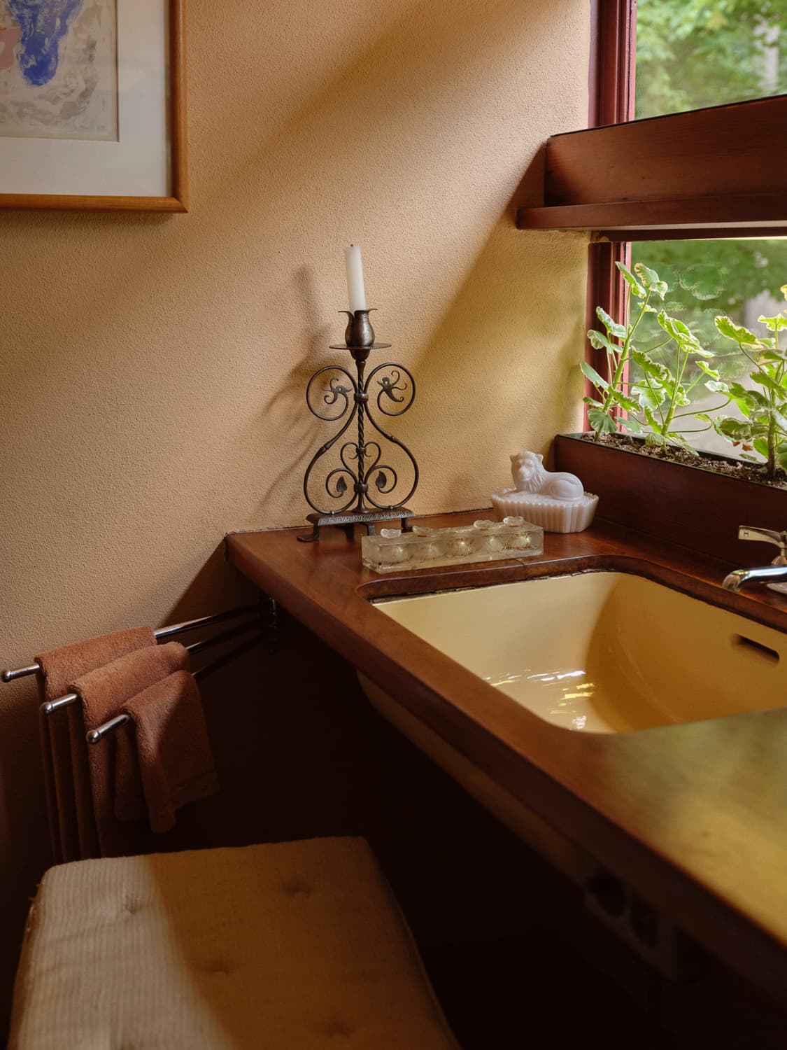 Fallingwater bathroom with gold toned tub, wrought iron candlestick, and window planter box