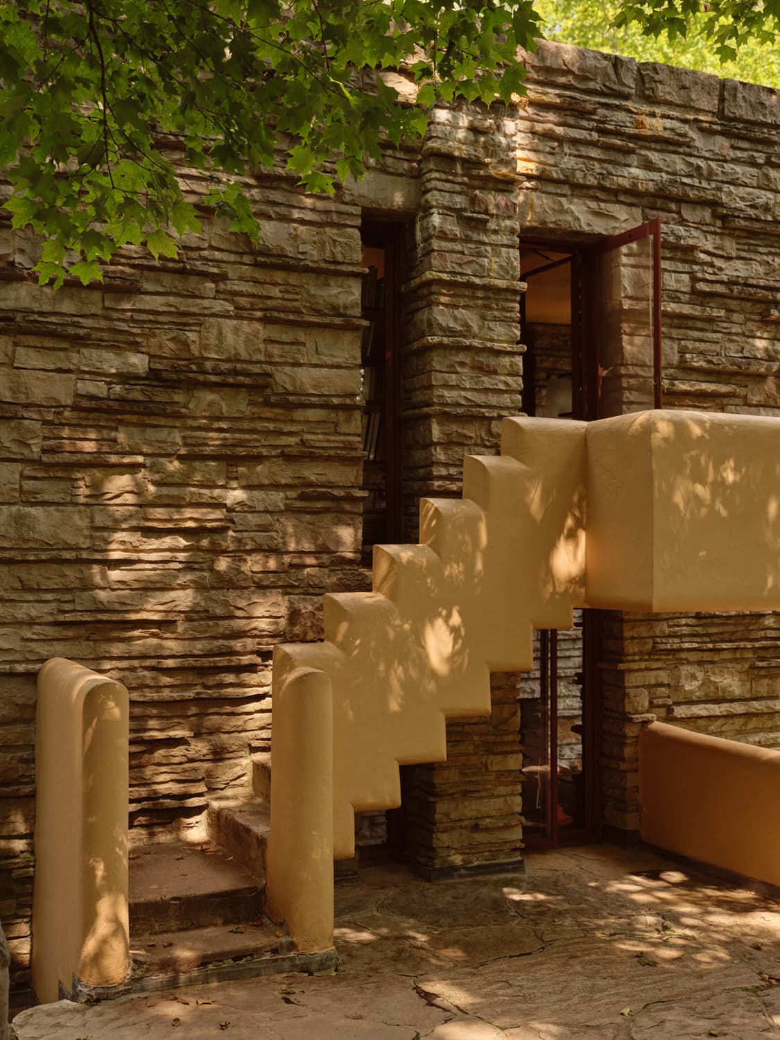Stone facade and stepped concrete railing of the guest house stairway at Fallingwater