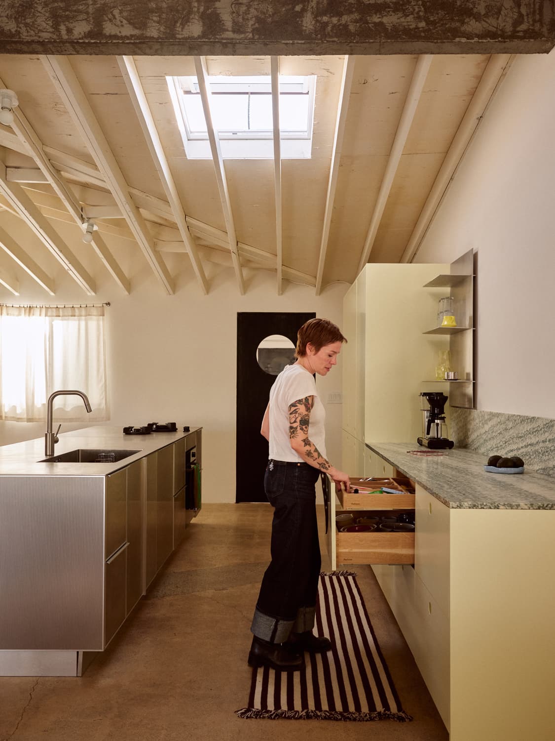 Bethany Brill opening a kitchen drawer under a skylight in her renovated Costa Mesa home