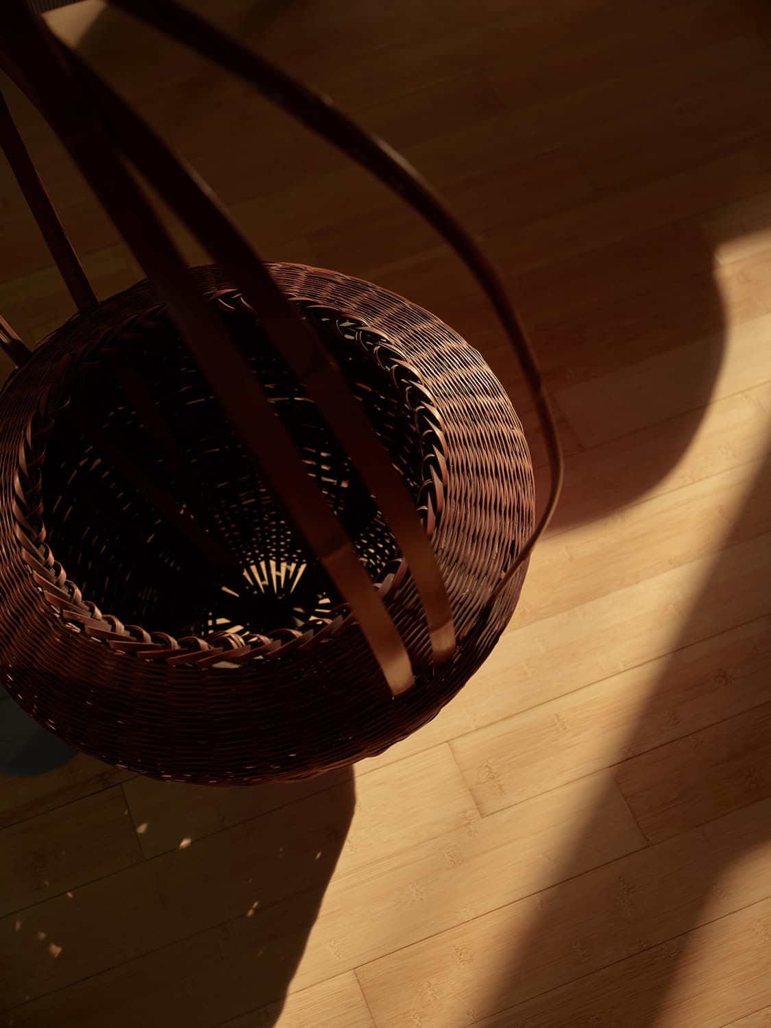 Overhead detail of a woven Japanese basket on sunlit bamboo hardwood floor