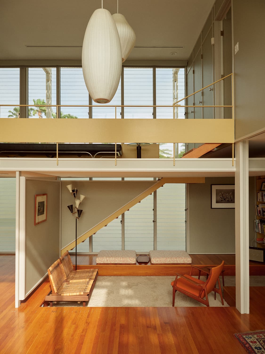Umbrella House interior with Nelson bubble pendants, open staircase, mezzanine railing, and wood floors