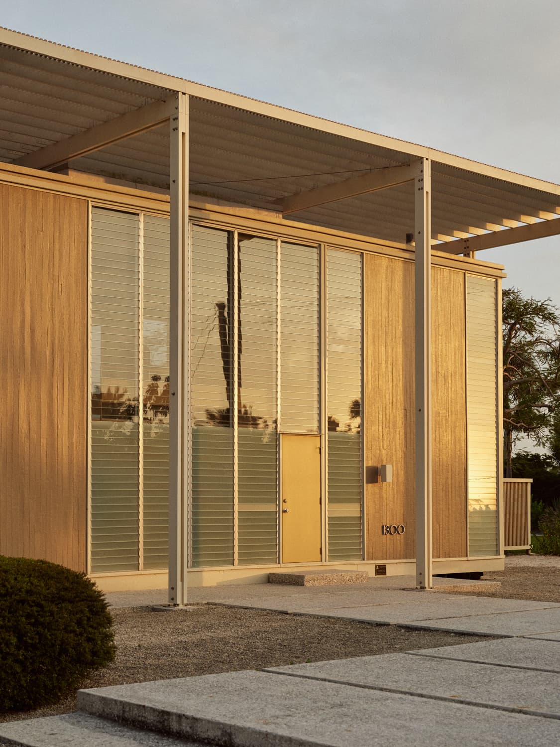 Umbrella House front entry at golden hour with louvered glass, bamboo panels, and slatted roof