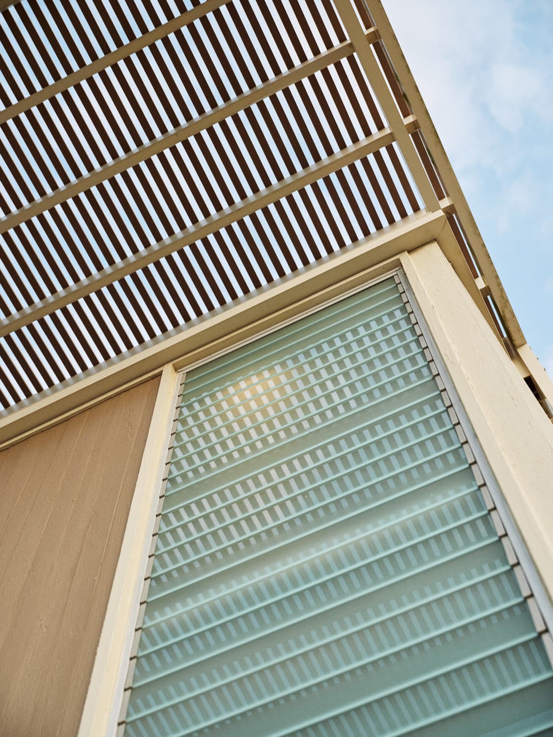 Looking up at the Umbrella House slatted roof overhang and louvered glass window detail