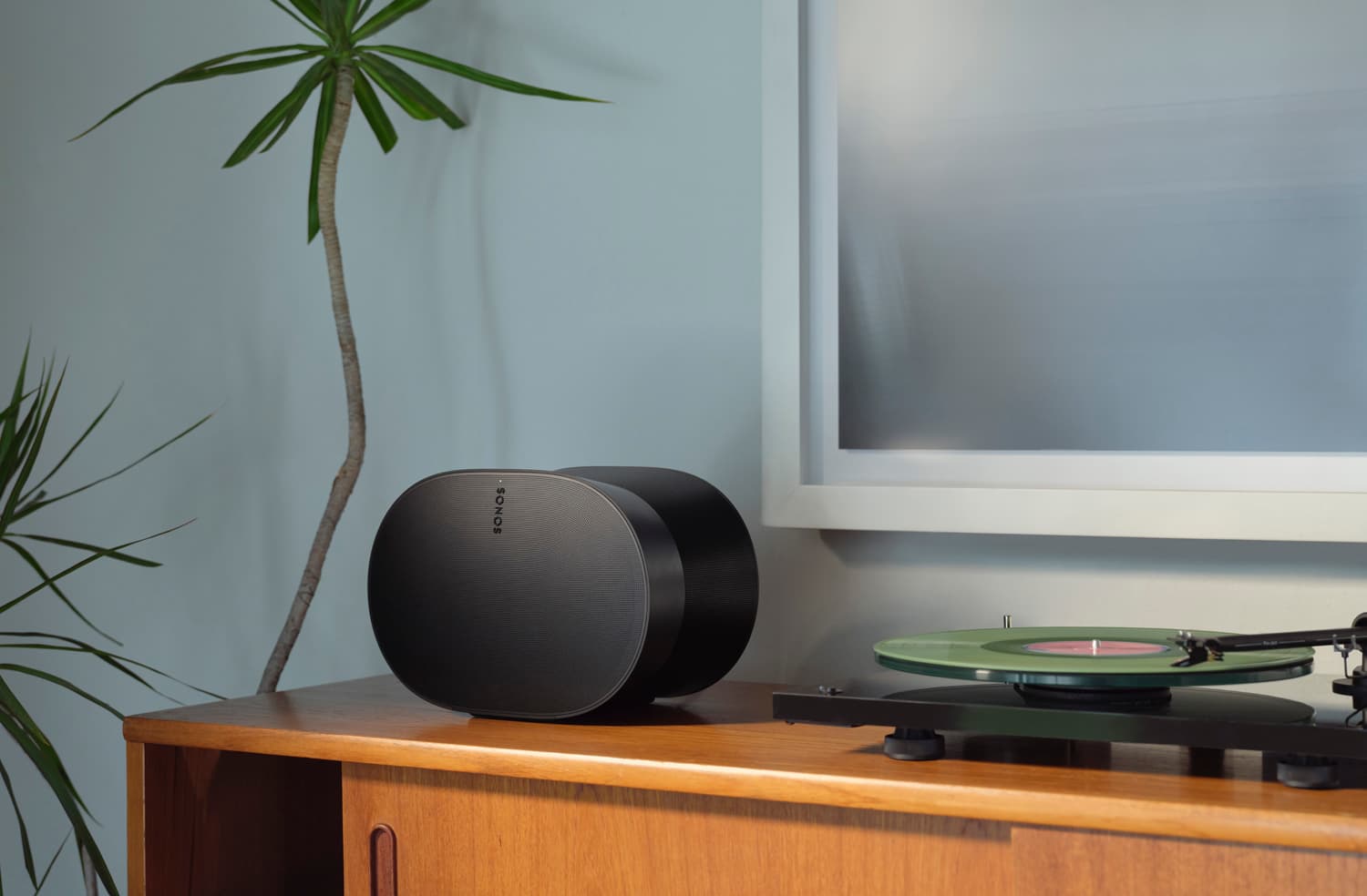 Pair of black Sonos Era 300 speakers on a mid-century credenza next to a vinyl turntable